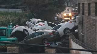 山西吕梁离石一路口多辆私家车遭洪水堆叠 市民冒雨寻车